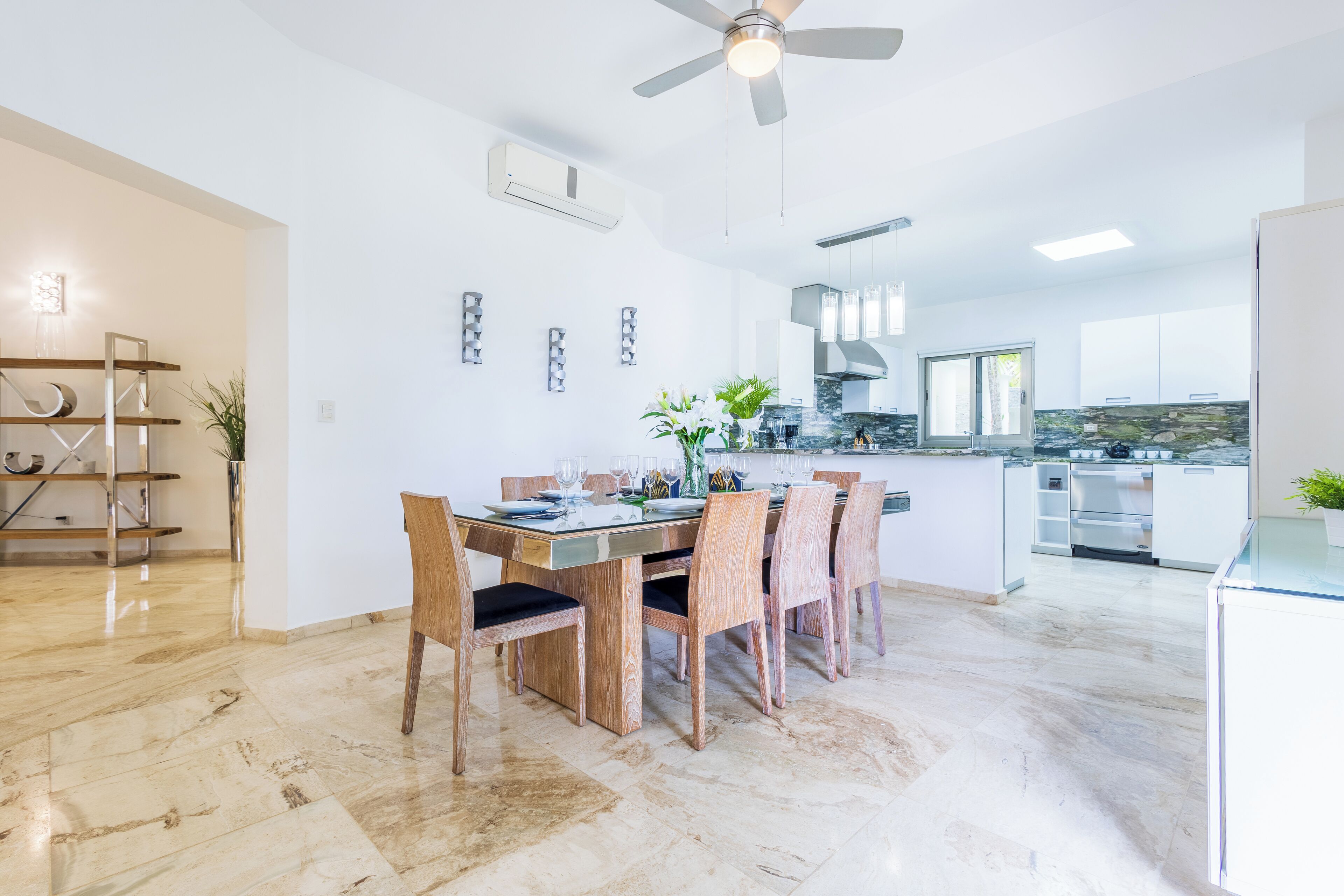 A modern kitchen with white cabinets, a granite countertop, and a dining area with a wooden table and chairs.