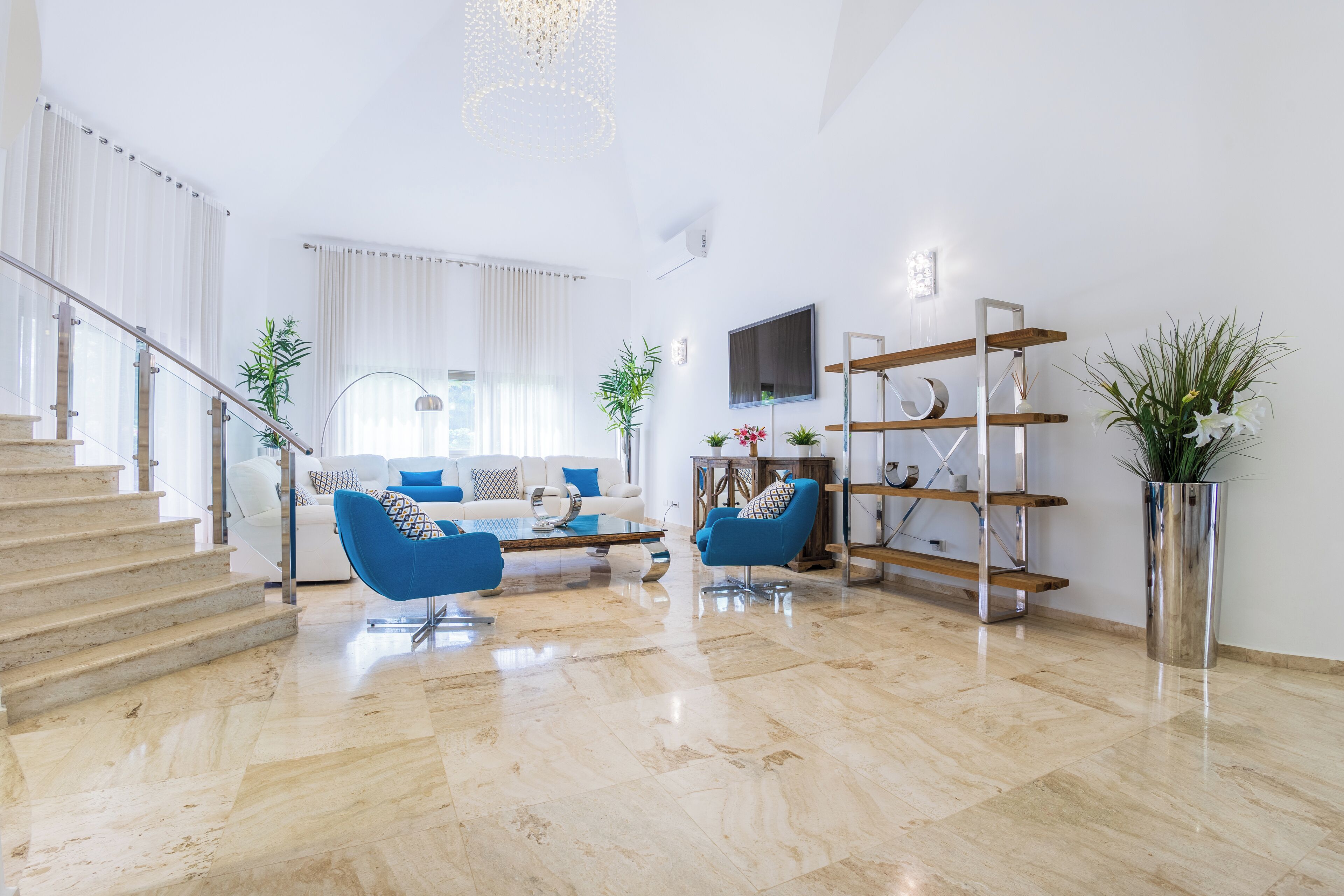 A spacious living area with a staircase, a sofa set, a coffee table, and a TV mounted on the wall.