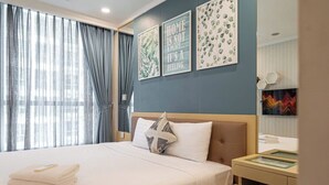 Une chambre d’hôtel avec un lit, une table de chevet, un miroir et des œuvres d’art accrochées au mur.