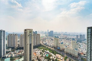 A high-rise building with multiple floors, surrounded by a dense urban area with various buildings and a river in the background. - The Peninsula Landmark Central Park (Ho Chi Minh)