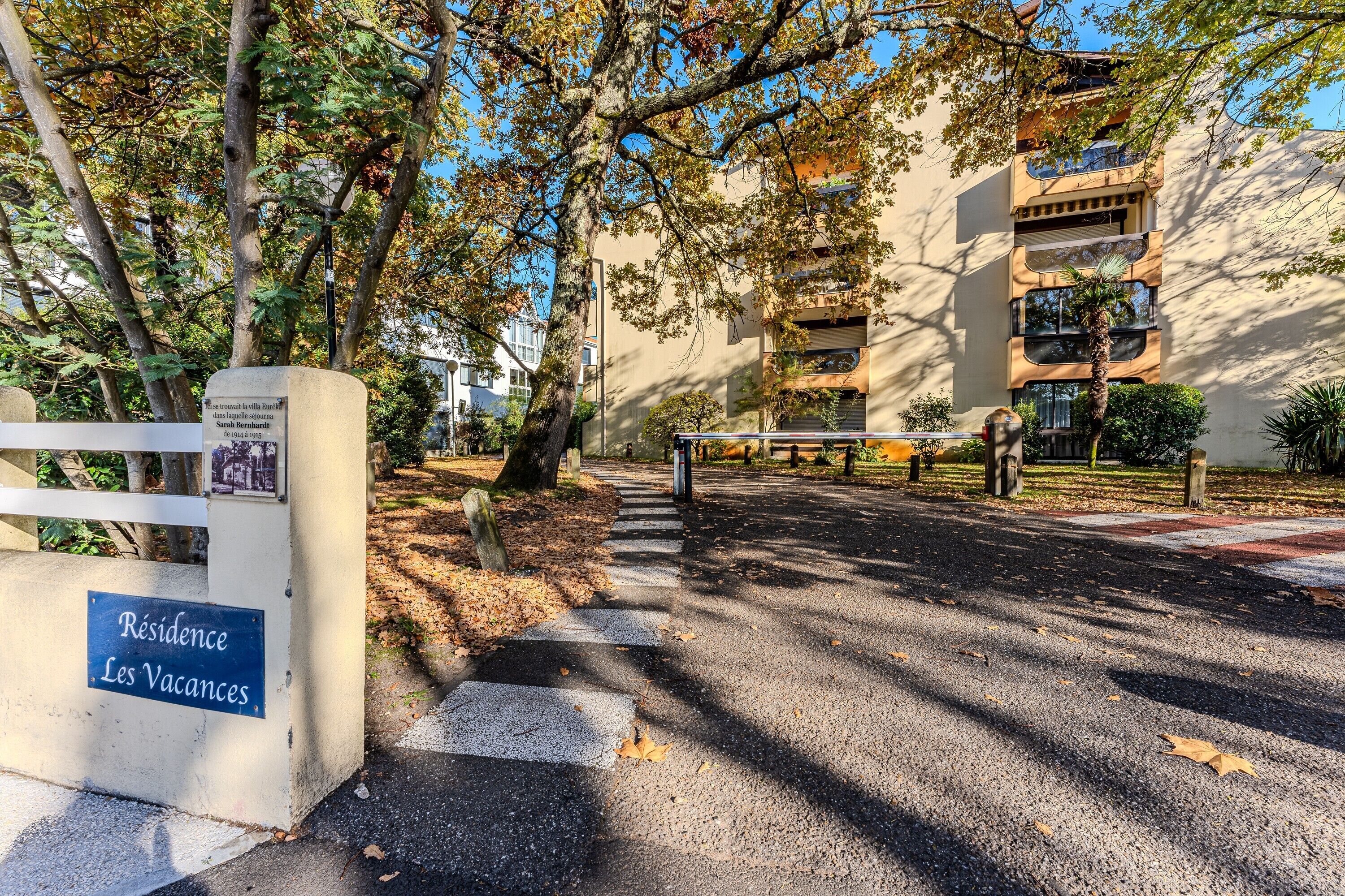 Una entrada con portón a un edificio residencial con un cartel que indica 'Residence Les Vacances'.