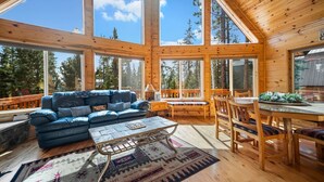 Una cabaña amplia con una gran mesa de comedor, sillas de madera y un sofá azul.