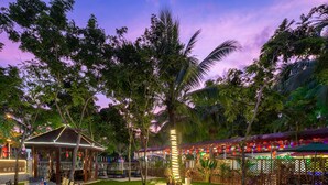 An outdoor dining area with tables and chairs, a covered seating area, and a well-maintained lawn. - Sanya Anyun  Coastal Lodge (Sanya)