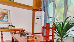 A wooden dining table with chairs, a painting, a cabinet, and a potted plant. - Sanya Anyun  Coastal Lodge (Sanya)