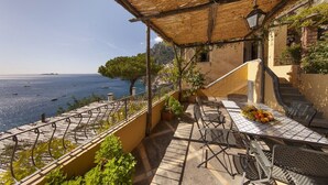 Une terrasse avec une table dressée pour le dîner, offrant une vue sur la côte.