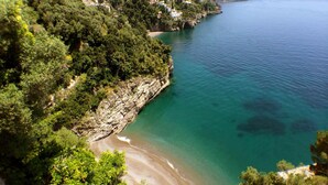 Un paysage côtier caractérisé par une côte rocheuse, une plage de sable et une végétation luxuriante.