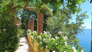 Un sentier bordé de fleurs blanches et de piliers en briques qui mène à un plan d’eau.