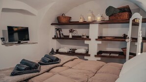 Ein gemütliches Schlafzimmer mit einem Bett, einem Fernseher auf einem Regal und Regalen mit Handtüchern und Körben.