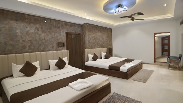Una habitación de hotel moderna con dos camas, un ventilador de techo y una lámpara circular original.