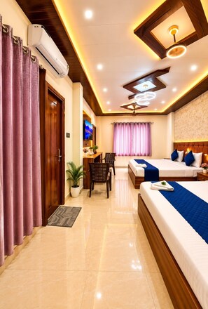 Habitación de hotel con cama, escritorio, silla, televisor y ventilador de techo.