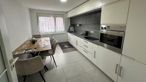 A modern kitchen with white cabinets, a black countertop, and stainless steel appliances. - Stylish apartment in a modern ambience in Tuttlingen (Tuttlingen)