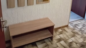 Una habitación con un banco de madera, un espejo en la pared y una puerta que da a otra estancia.