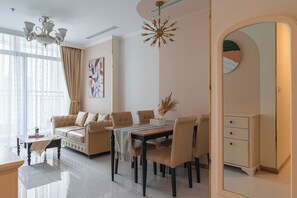 A modern living room with a sofa, dining table, and chairs, a chandelier, and a large mirror. - Everland The Landmark (Ho Chi Minh City)