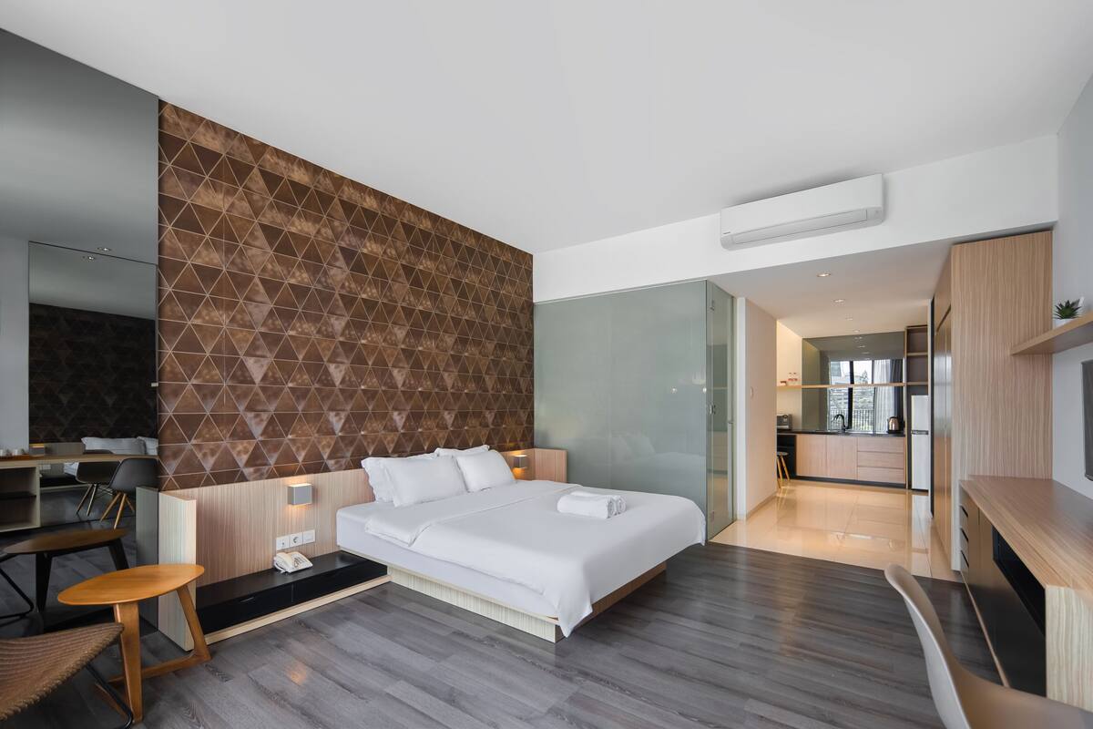A modern hotel room with a large bed, a desk, and a seating area.