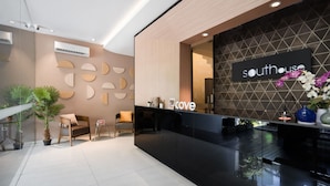 A modern reception area with a black reception desk, a sign reading "southhouse cove", and a geometric wall design. - Cove Southouse Residence (Jakarta)