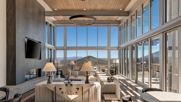 A spacious, well-lit lounge area with large windows offering mountain views, modern furniture, and a flat-screen TV mounted on the wall. - All-Season Escape | Ski-In/Out + Hot Tub + Clubhouse Amenities Canyons Village (Park City)