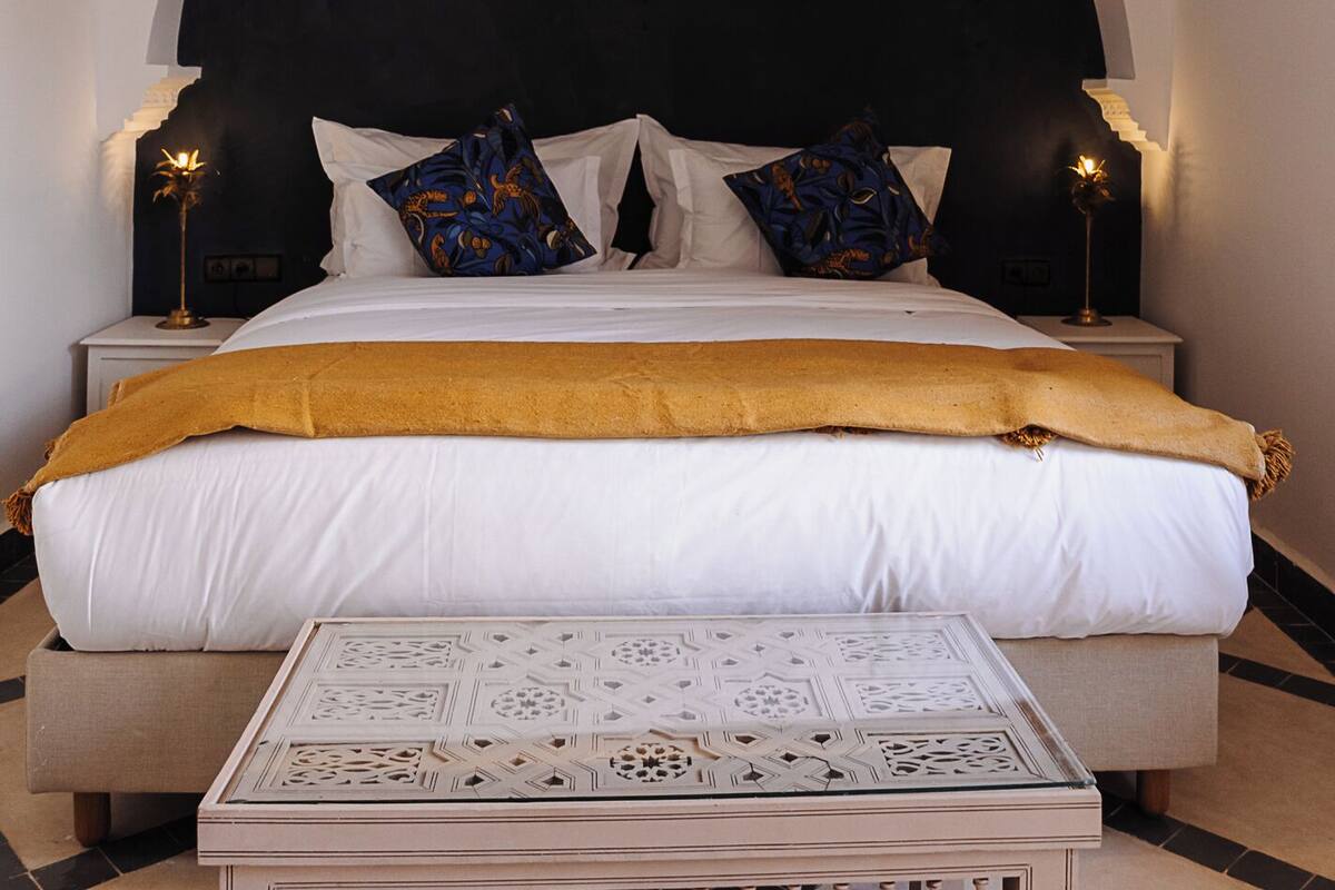 A bedroom with a large bed, a decorative ceiling light, and two bedside lamps.