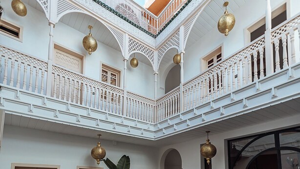 A courtyard with a pool, white balconies, and traditional doors. - Riad le terra cotta (Marrakech)