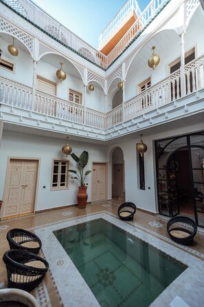 A courtyard with a pool, white balconies, and traditional doors. - Riad le terra cotta (Marrakech)