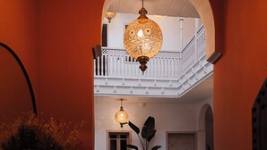 An indoor pool area with a tiled floor, a wooden bench, and a hanging light fixture. - Riad le terra cotta (Marrakech)