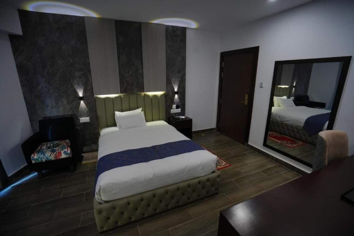 Une chambre d’hôtel moderne, dotée d’un grand lit, de tables de chevet, d’un miroir et d’une armoire.