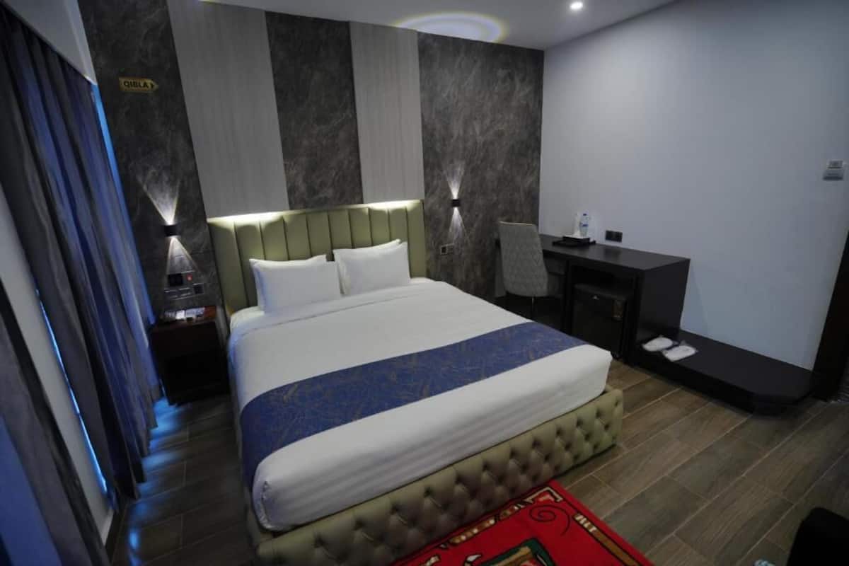 Une chambre d’hôtel avec un grand lit, un bureau et une table de chevet.
