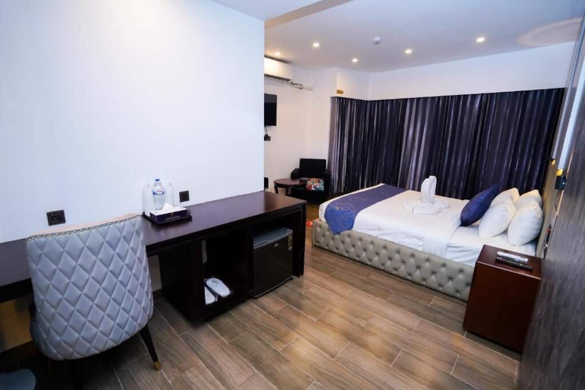 Une chambre d’hôtel équipée d’un lit, d’un bureau, d’une chaise, d’une petite armoire et d’un téléviseur.