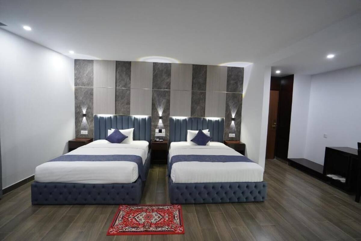 Une chambre d’hôtel avec deux lits, un tapis rouge et un mur entièrement recouvert de miroirs.