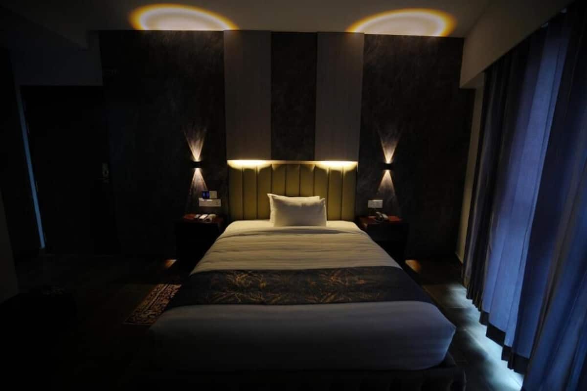 Une chambre d’hôtel dotée d’un grand lit, de deux tables de chevet et d’une tête de lit avec éclairage intégré.