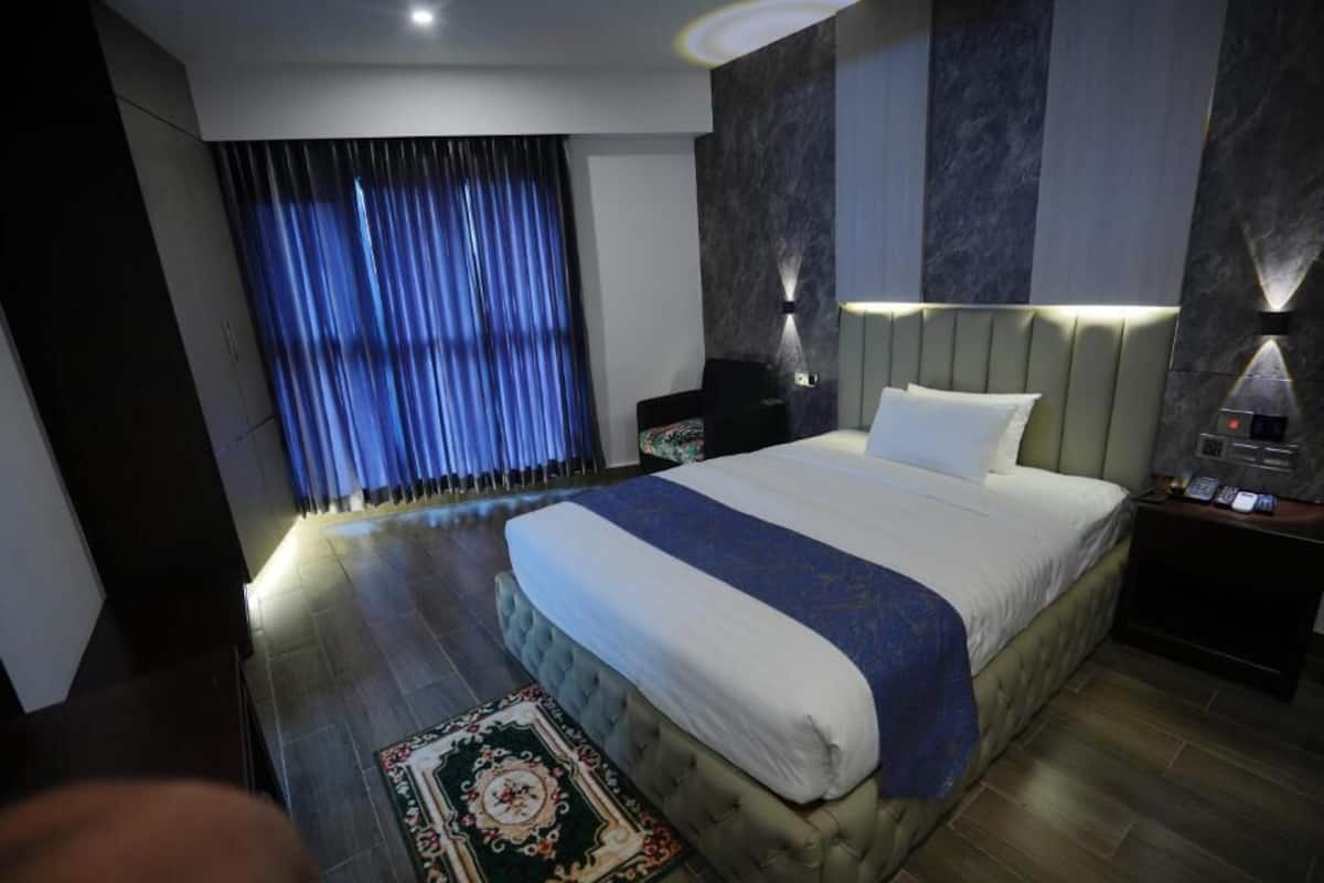 Une chambre moderne avec un grand lit, une table de chevet, une lampe et une fenêtre avec des rideaux.