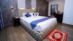 Una moderna camera d'albergo con un ampio letto, un comodino, una scrivania e uno specchio.