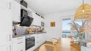 Una cucina moderna con mobili bianchi, forno integrato, microonde e un'ampia finestra con vista su un balcone.