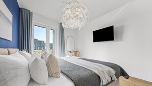 Una camera da letto moderna con un letto, una televisione e vista sugli edifici.