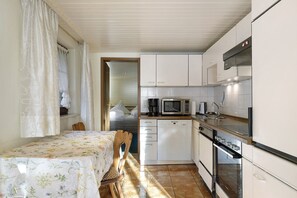 A compact kitchen with white cabinets, a microwave, a coffee maker, and a stove.