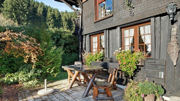 Una casa in legno con patio in pietra, mobili in legno e piante in vaso.