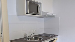 A compact kitchen with white cabinetry, a stainless steel sink, a microwave, and a dishwasher. - Studio in the Bassin à flots district, at the foot of the streetcar! (Bordeaux)