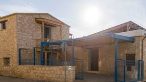 Un bâtiment en pierre doté d’un balcon, d’une entrée couverte et d’un portail bleu.