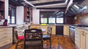 Een keuken met houten kastjes, een granieten aanrecht, een eettafel met stoelen en een raam met jaloezieën.