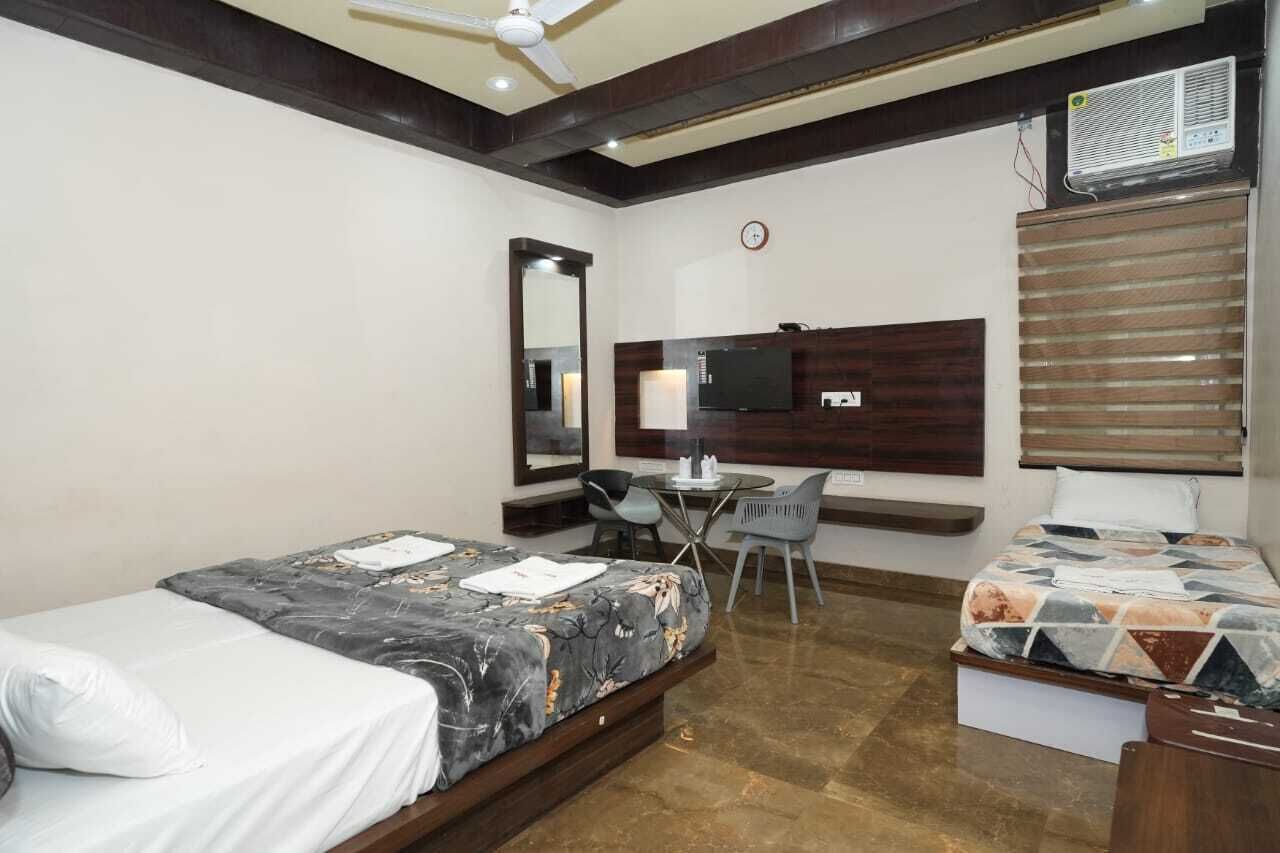 Habitación de hotel con dos camas, un escritorio, una silla, un televisor y un ventilador de techo.