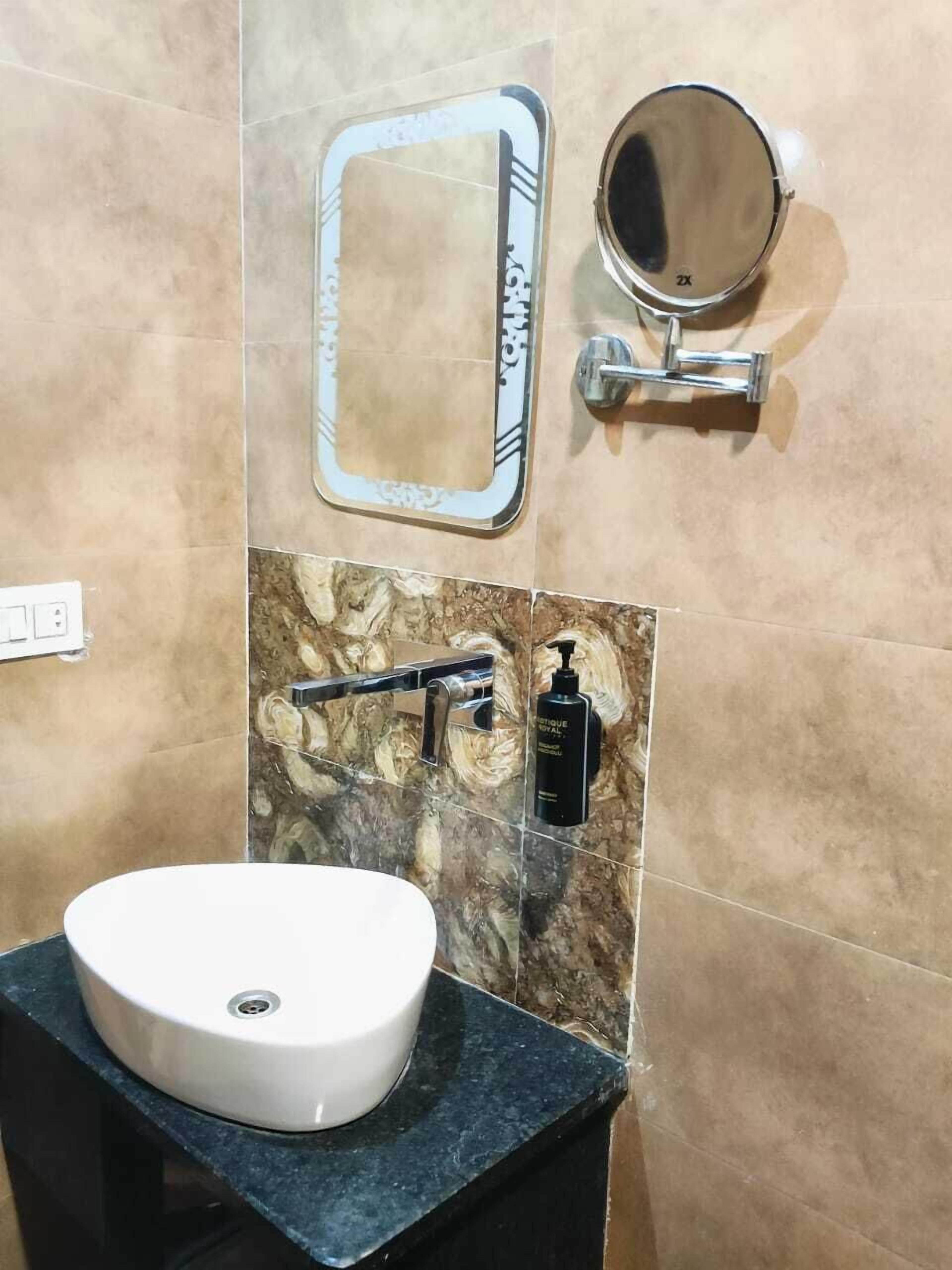Un baño con un lavamanos blanco, un espejo y un dispensador de jabón en la pared.