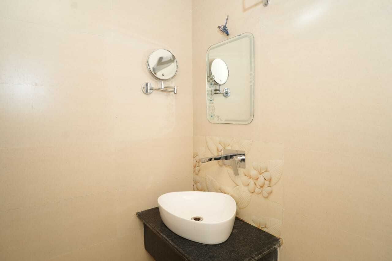 Une salle de bain avec un lavabo blanc, un miroir rond et un miroir rectangulaire accroché au mur.