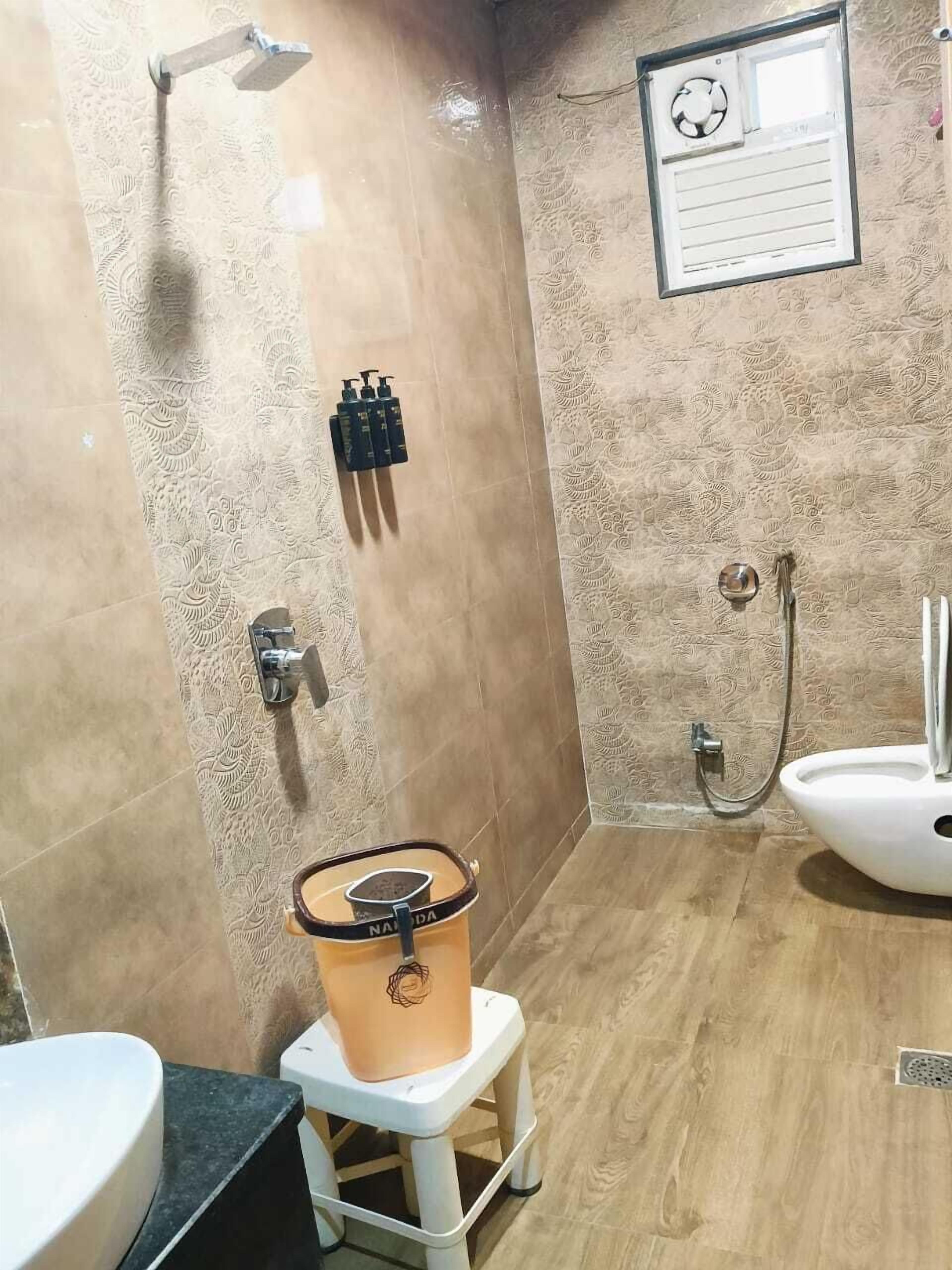 Un baño con ducha, inodoro, lavabo y un espejo adosado a la pared.