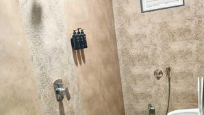 A bathroom with a shower, toilet, sink, and a wall-mounted mirror. - Raj Mahal Hotel (Varanasi)