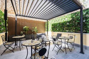 An outdoor patio area with tables and chairs, a pergola, and a wall covered in greenery. - The Echo of the Center Room San Gennaro [Charming in the Heart of Naples] (Napoli)