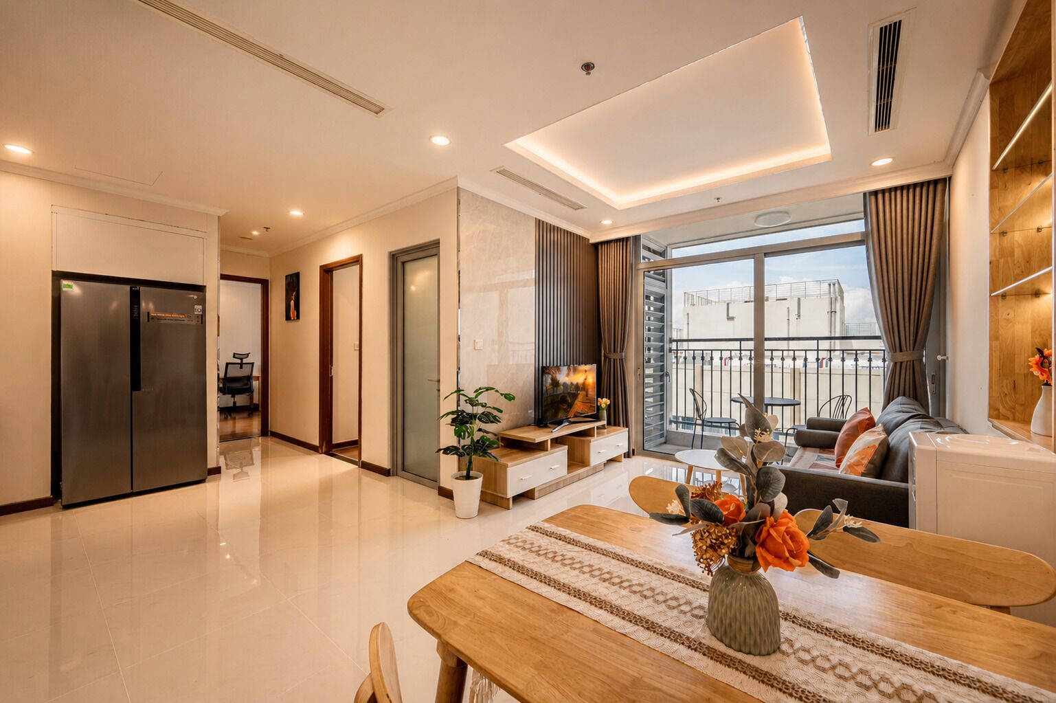 A modern living room with a dining area, a large window, and a balcony.