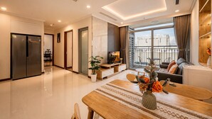 A modern living room with a dining area, a large window, and a balcony. - Vinhomes Skyline Apartment Saigon (Ho Chi Minh City)