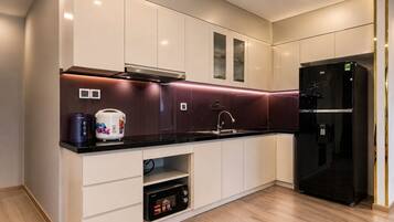 A modern kitchen with white cabinetry, a black refrigerator, and a microwave.