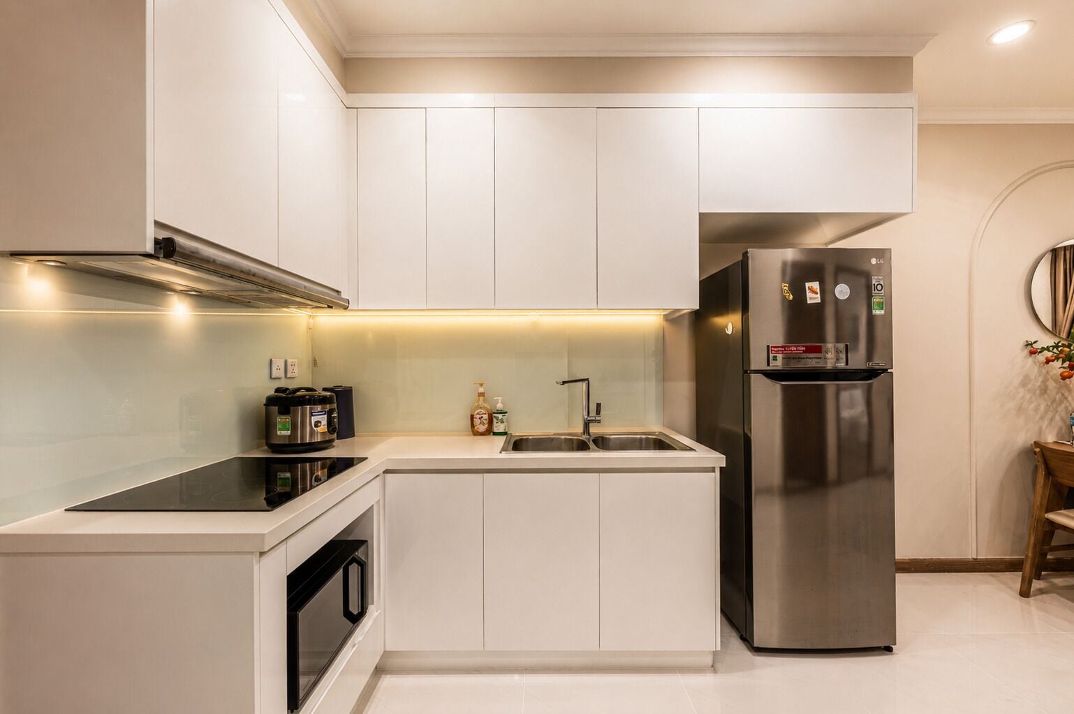 A modern kitchen with white cabinetry, a stainless steel refrigerator, a built-in oven, and a microwave.