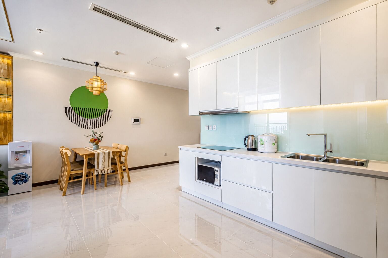 A modern kitchen with white cabinets, a stainless steel sink, and a built-in oven.