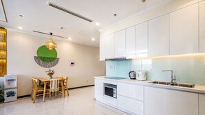A modern kitchen with white cabinets, a stainless steel sink, and a built-in oven. - Vinhomes Skyline Apartment Saigon (Ho Chi Minh City)